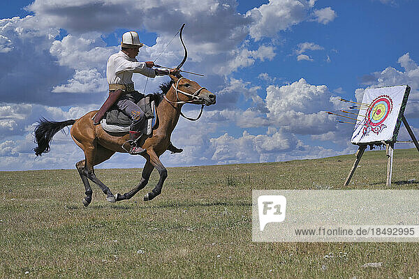 Kyrgyz nomad shooting arrows at a target while galloping  Song Kol lake  Naryn region  Kyrgyzstan  Central Asia  Asia