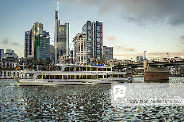 View of city skyline  river cruise boat and River Main at sunset  Frankfurt am Main  Hesse  Germany  Europe