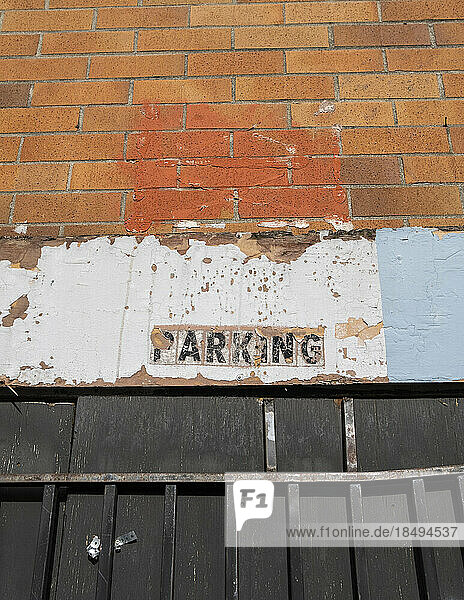An old PARKING sign on a building wall.
