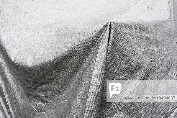 Black and white image  folds of tarpaulin draped across objects.