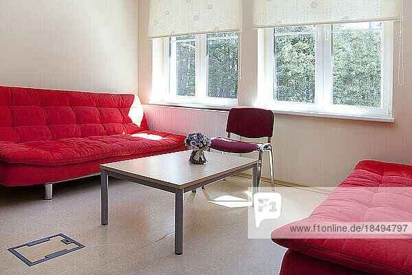 A staff room in a school  two red sofas and a table.