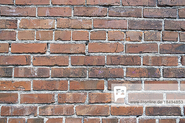 A brick wall  red clay bricks laid in a regular pattern to make a wall.