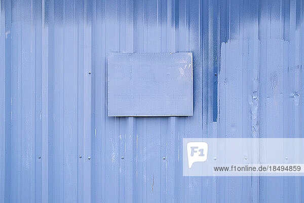 A painted sign on painted blue building wall.