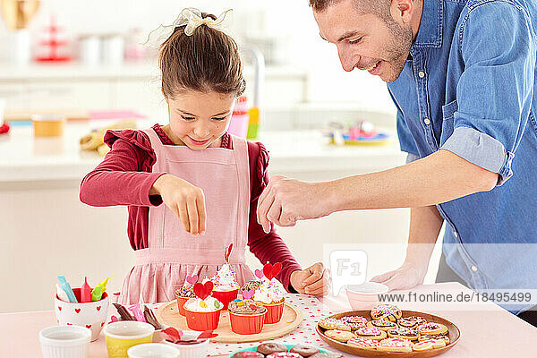 Smiling young girl making sweets with her dad