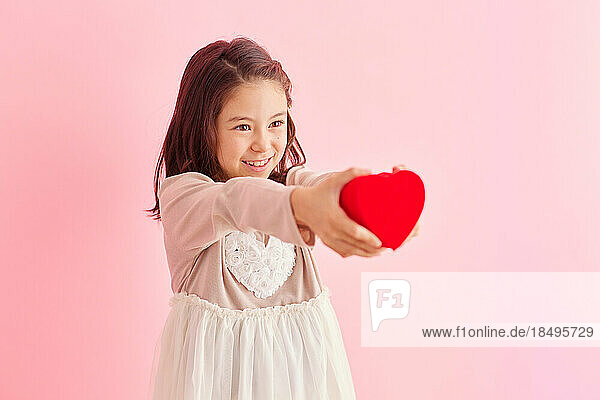 Smiling young girl holding heart