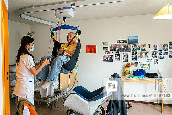 Caregiver preparing the bedtime of a disabled patient in his room at the retirement home.