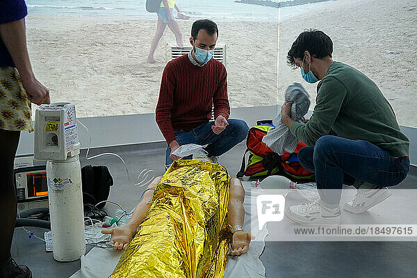 Emergency medicine students attends a circumstantial emergency simulation course led by two emergency physicians. Simulation of a drowning case at the beach. Realistic images and sound are projected all around the room to immerse students in total immersion. A young girl came up to the water's edge in cardiac arrest.