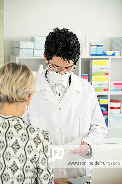 Client presenting her prescription to a pharmacist.