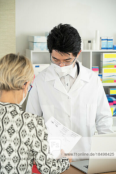 Client presenting her prescription to a pharmacist.