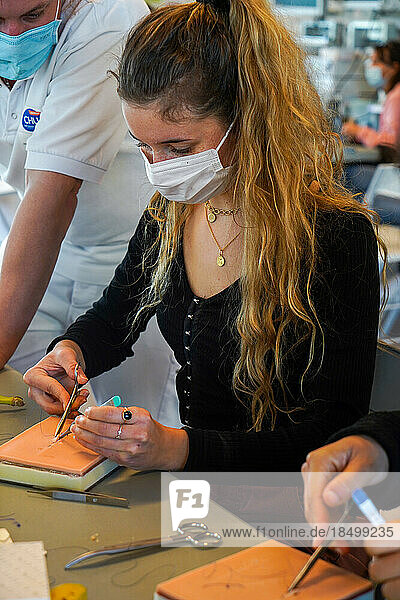 5th year students during a sewing workshop. The students learn the gestures of suturing on false epidermis or bananas. A professor of emergency medicine directs the suturing course.