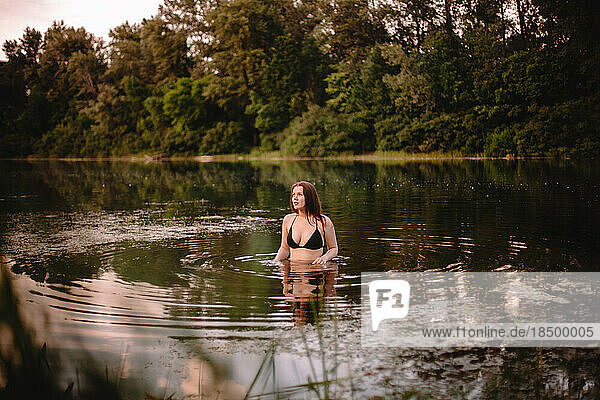 Young woman standing in lake against trees