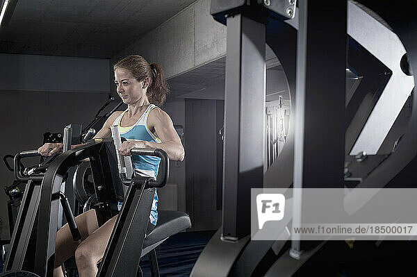 Mid adult woman doing exercise on exercise machine in the gym  Bavaria  Germany
