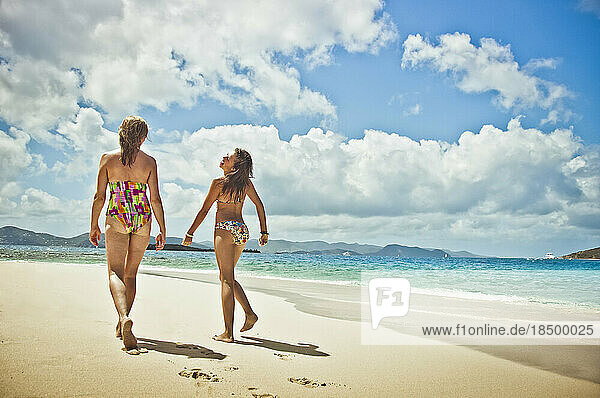 Teenage girl and mother strolling on the beach.