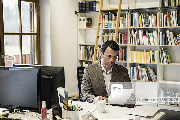Mature businessman reading papers in an office  Bavaria  Germany
