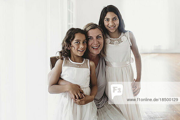 Portrait of mother and two daughters in natural light studio smiling
