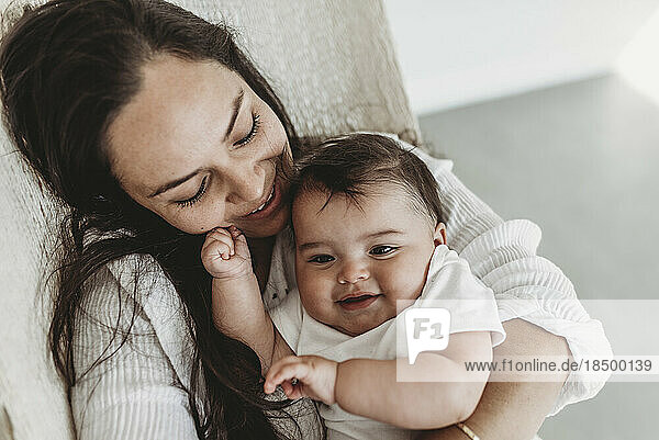 Mother and baby daughter cuddling in hammock in natural light studio