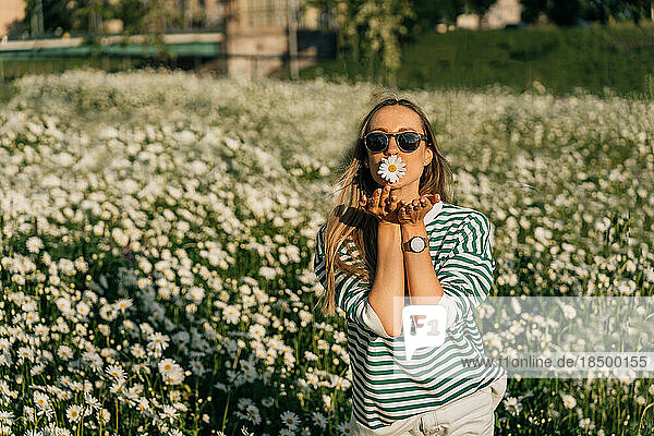 Woman in striped pullover sends air kiss among flower field