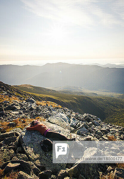 Woman napping on rock in morning on top of mountains