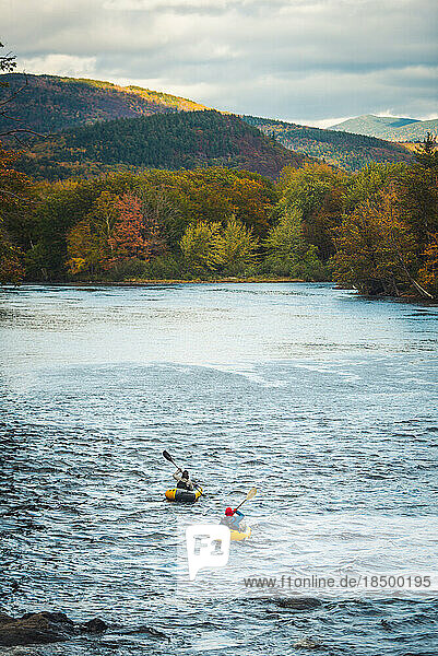 Two paddlers going down river with fall foliage