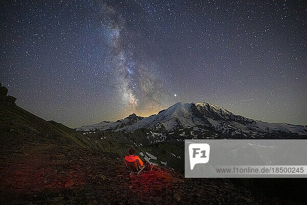 A Man is Sitting and Looking at the Milky Way Over Mt. Rainier