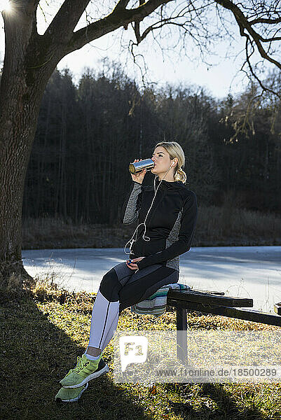 Young woman drinking water after working out in nature