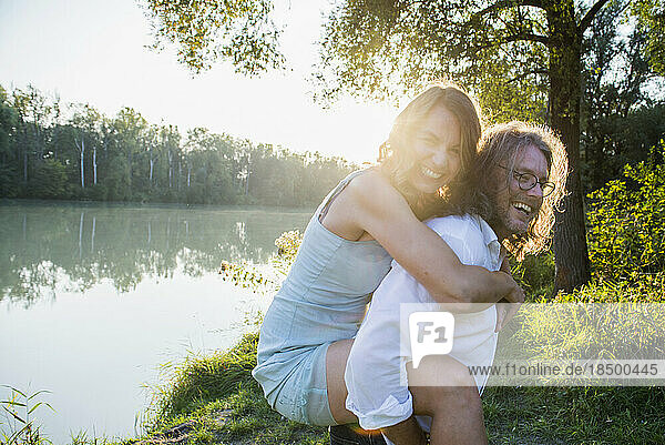 Couple enjoying piggyback by river  Bavaria  Germany