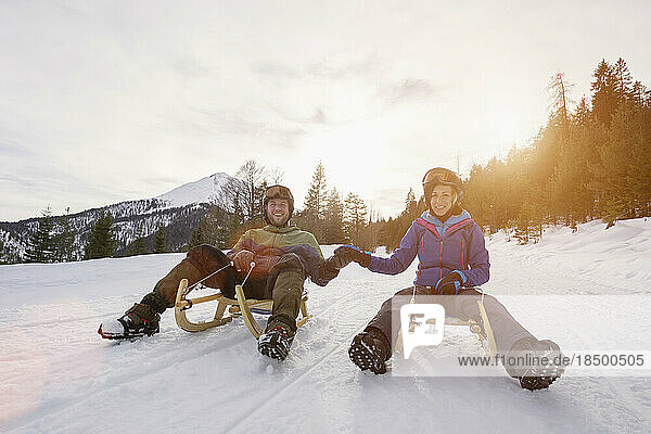 Couple sledding on winter landscape
