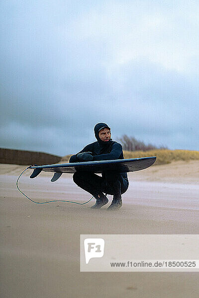 surfing in Kamchatka. Man in a wetsuit with a surfboard on the s
