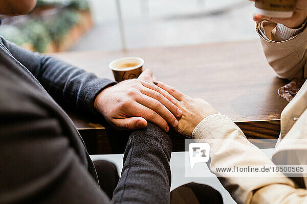 couple holding hands enjoying coffee by the window
