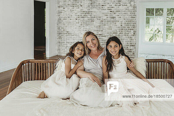 Mother and daughters sitting on couch in natural-light studio