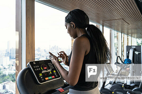 black woman running on a treadmill on the gym speaking with her phone