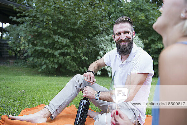 Young man opening wine bottle on picnic with his wife  Bavaria  Germany