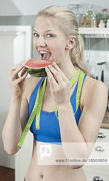 Young woman eating slice of watermelon in the kitchen  Bavaria  Germany