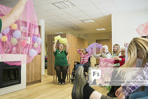 Nurse guiding girls and senior women for gentle sports exercise in rest home