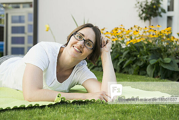 Portrait of woman lying on a blanket at garden of her house  Bavaria  Germany
