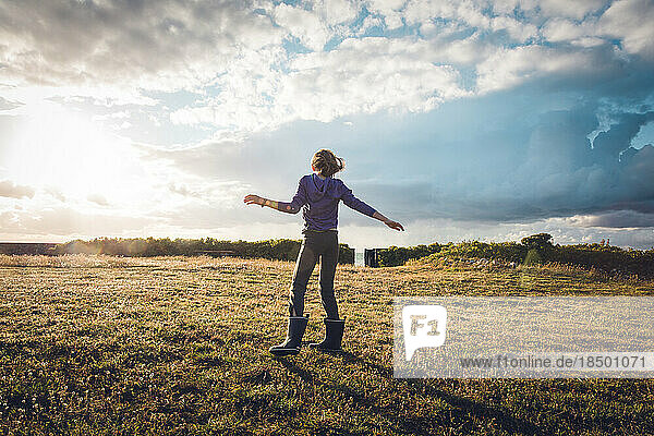 Young Girl Feeling the Wind With Dramatic Summer Sky