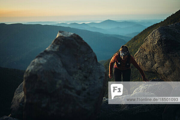 Woman hiking between boulders at sunrise in white mountains