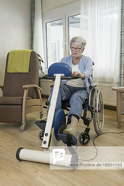 Senior woman on wheelchair exercising on exercise bike in rest home