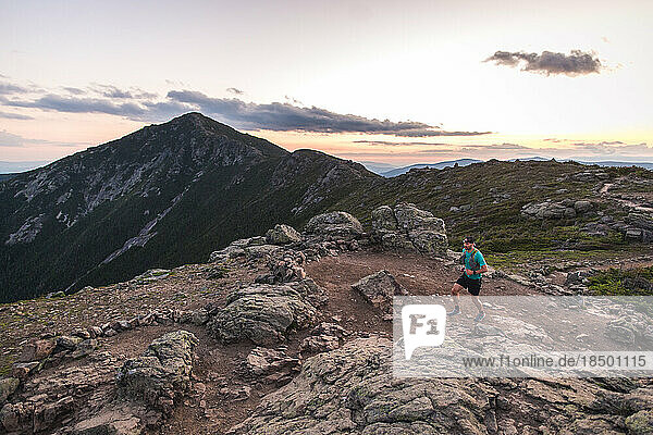 Man running on the Franconia Ridge at sunrise with mountains