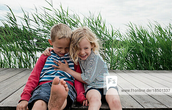 brother and sister hugging and laughing at the beach in summer