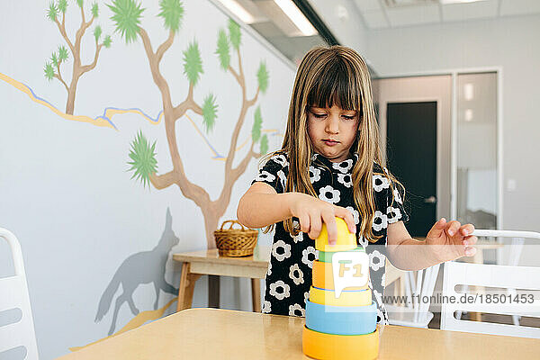Little girl stacks cylinders in an educational facility