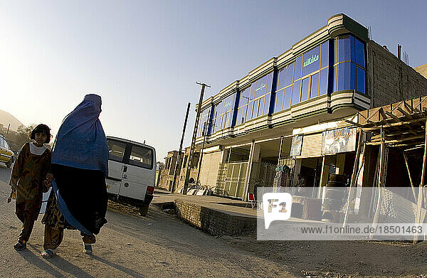 Woman in a burka walks past a newly constructed building in Kabul.