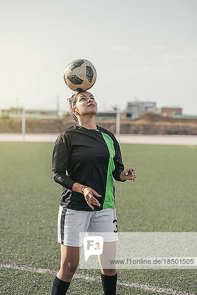 Young female soccer player balancing a ball on her head.