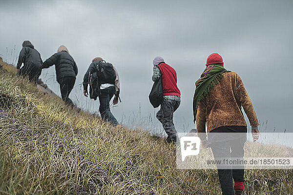 Group of friends hike up steep wild mountain slope in Scotland