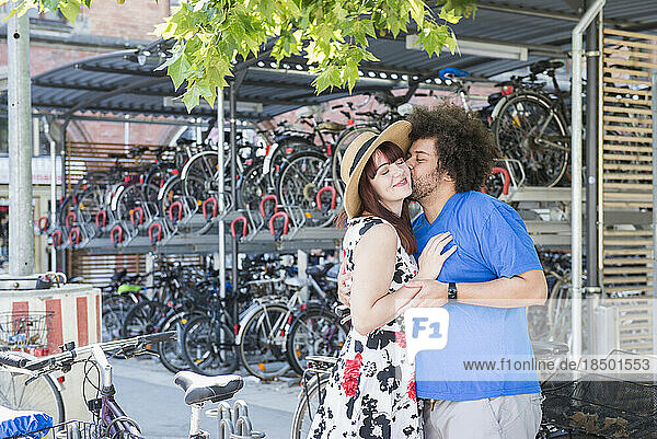 young couple kissing by bicycle parking
