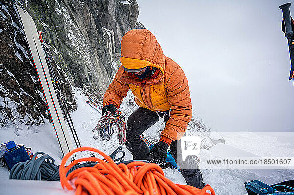 Man preparing gear for a winter ski-mountaineering in puffy jacket