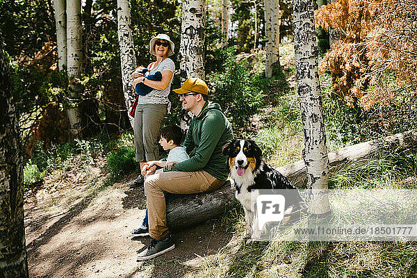 Family sitting outside in the forest with a dog happy in nature