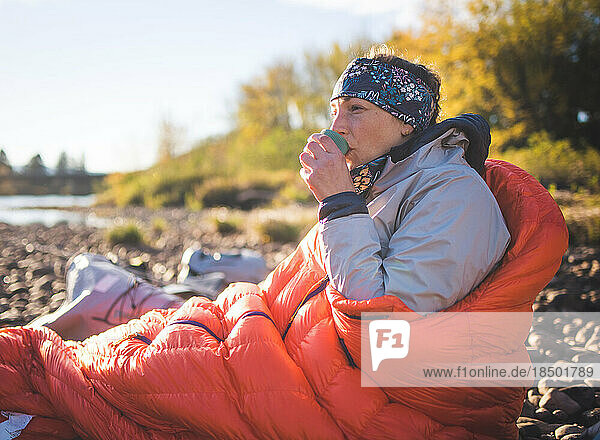 Woman in sleeping bag drinking out of a cup