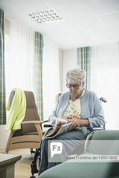 Senior woman reading magazine at rest home
