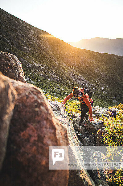 Woman hiking between boulders at sunrise in white mountains